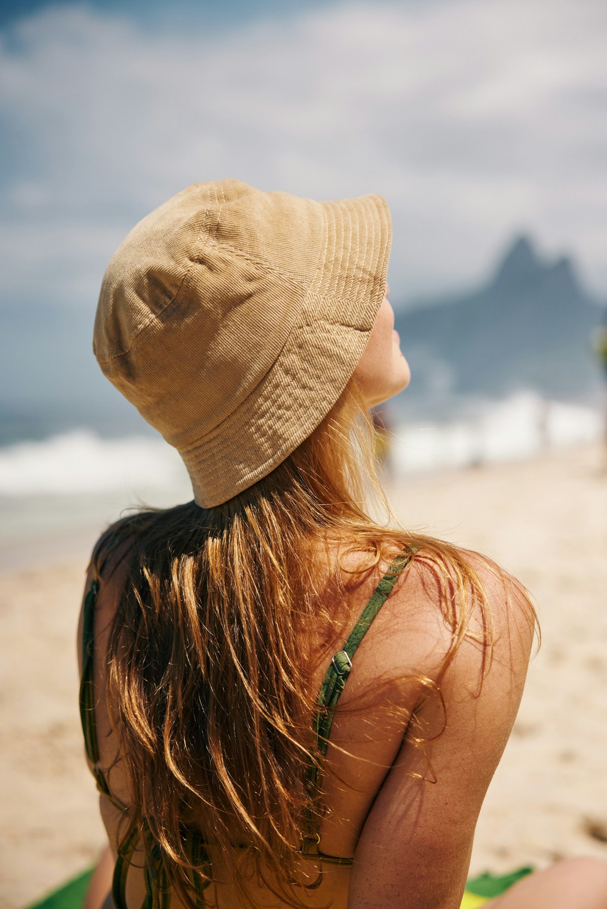 Woman in a sun hat at the beach, shielded from the midday sun